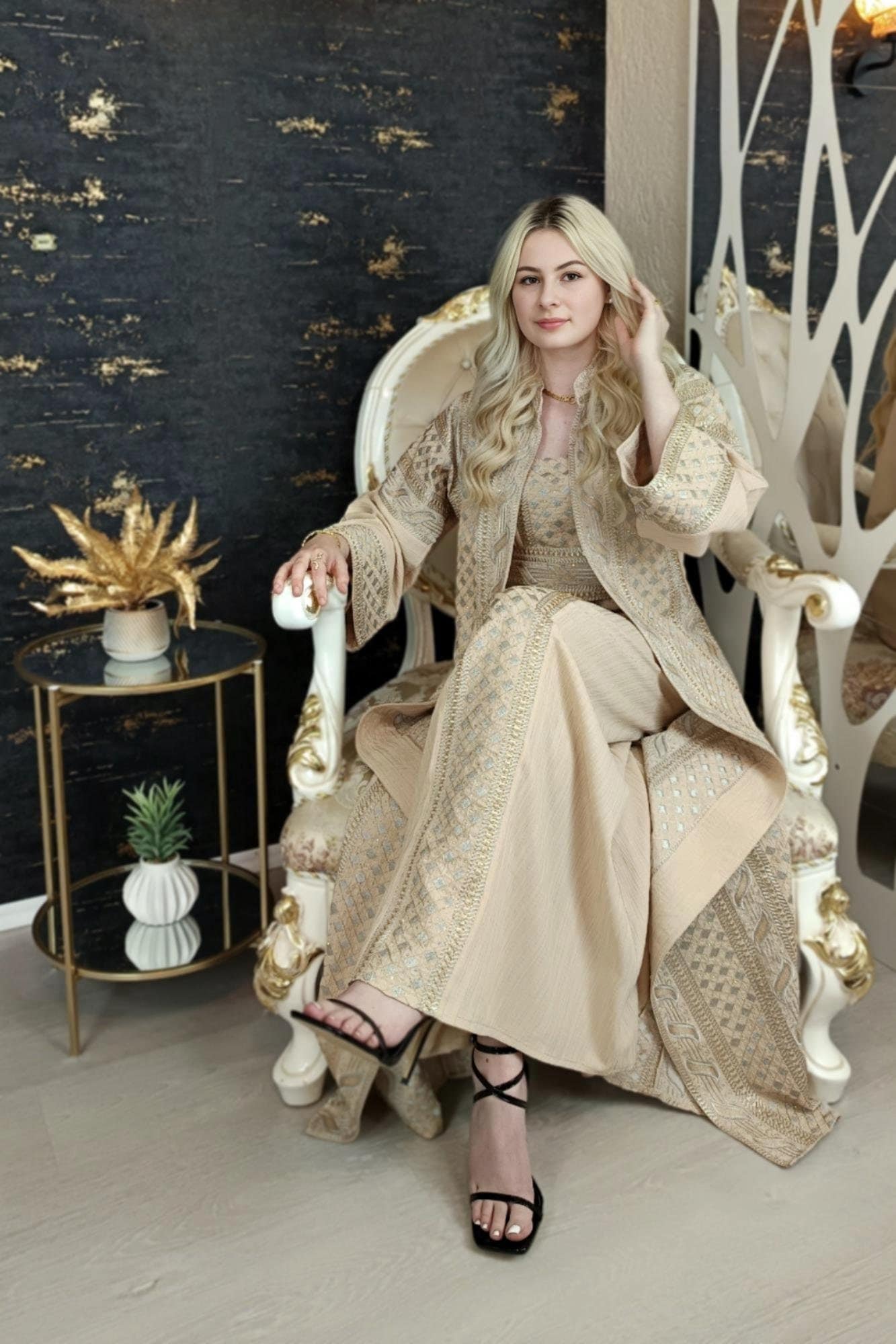 Könnte beinhalten: Eine Frau in einem langen, beige Kleid mit goldener Stickerei sitzt auf einem weißen, verzierten Stuhl. Sie trägt schwarze High-Heel-Sandalen. (etsy image id: 7678932704)